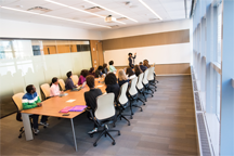 A meeting held in a long conference room.