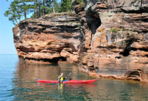 Kayakers enjoy exploring Apostle Islands' sea caves on calm Lake Superior