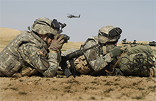 Two U.S. Army soldiers use binoculars and a riflescope to watch for insurgents